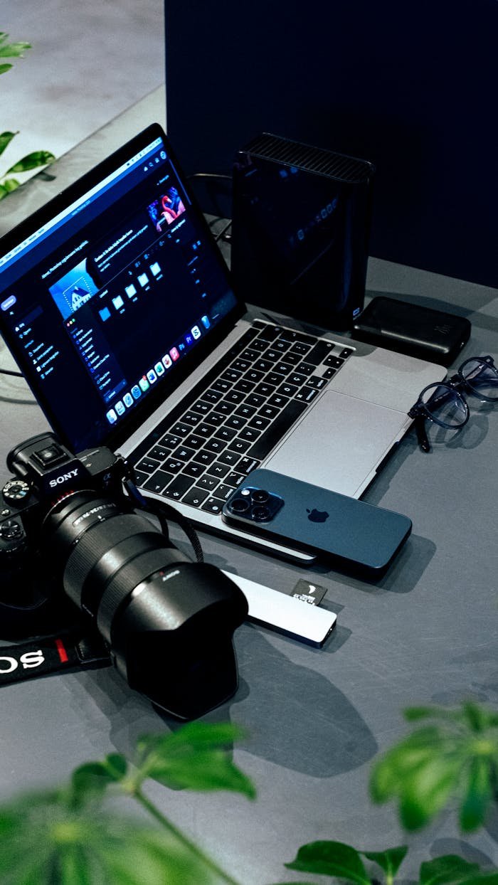 A creative workspace featuring a laptop, camera, and smartphone, ideal for photographers and videographers.