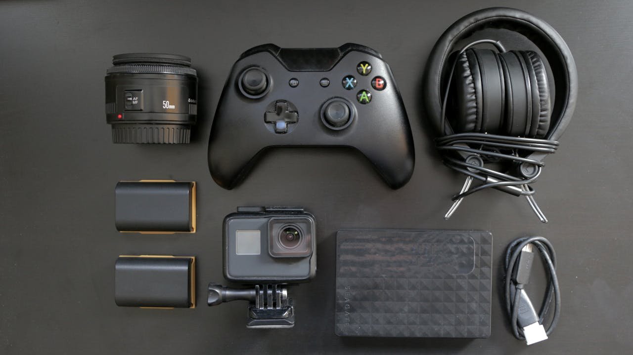 Top view of various gaming and tech gadgets, including a controller and headphones.